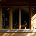 Abri de jardin en bois aménagé en bureau avec grandes fenêtres